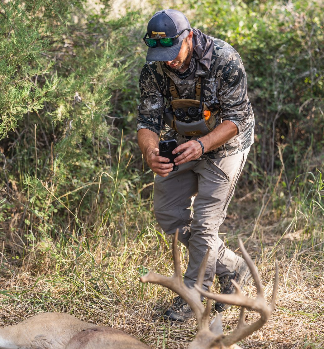 Hunter scanning a buck's antlers with a phone in the field
